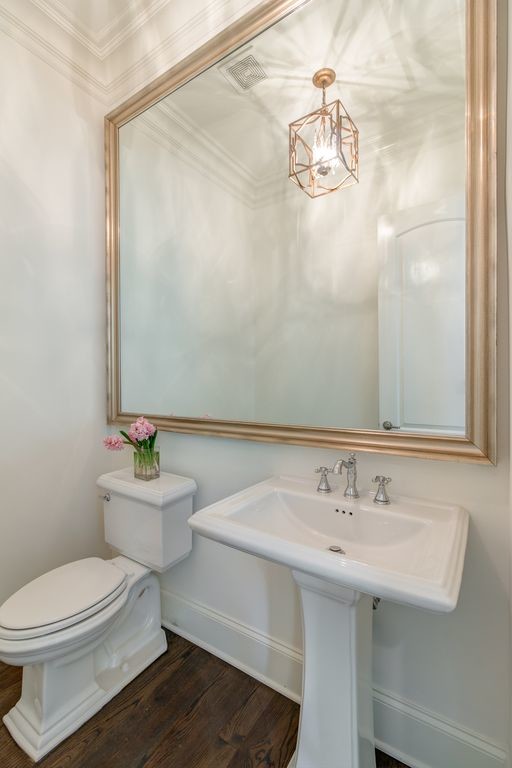 Cette photo montre un petit WC et toilettes tendance avec WC séparés, un carrelage beige, un mur beige, parquet foncé, un lavabo de ferme, un plan de toilette en surface solide, un sol marron et un plan de toilette blanc.