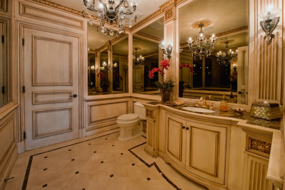 Idée de décoration pour un grand WC et toilettes tradition en bois clair avec un placard avec porte à panneau surélevé, WC séparés, des carreaux de miroir, un mur beige, un sol en carrelage de porcelaine, un lavabo encastré, un plan de toilette en marbre et un sol beige.