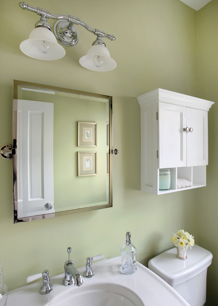 Idée de décoration pour un WC et toilettes tradition de taille moyenne avec un placard avec porte à panneau encastré, des portes de placard blanches, WC séparés et un mur vert.