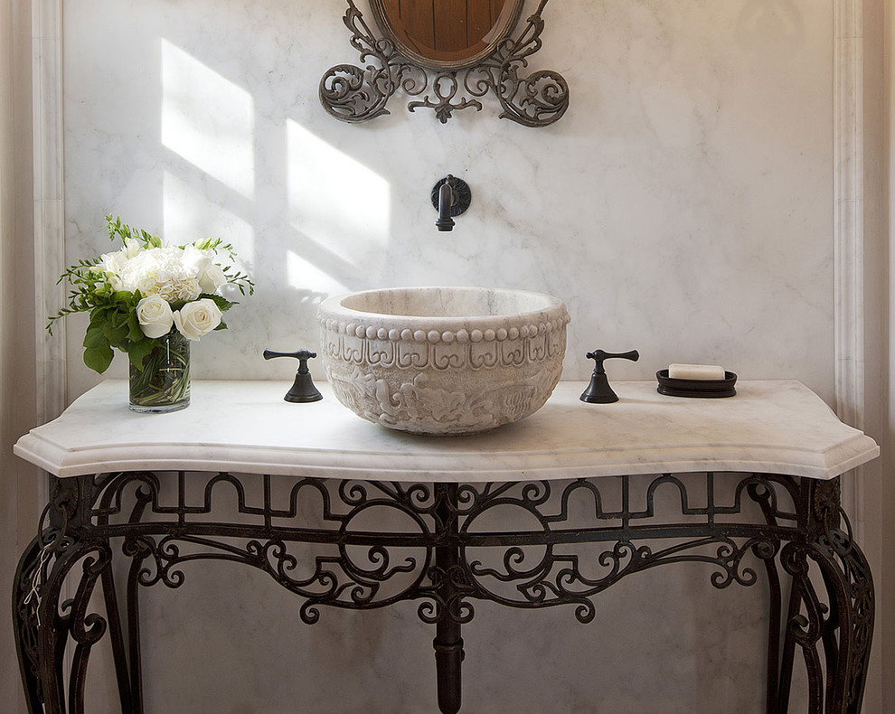 Example of a small tuscan stone slab powder room design in Santa Barbara with marble countertops and a vessel sink