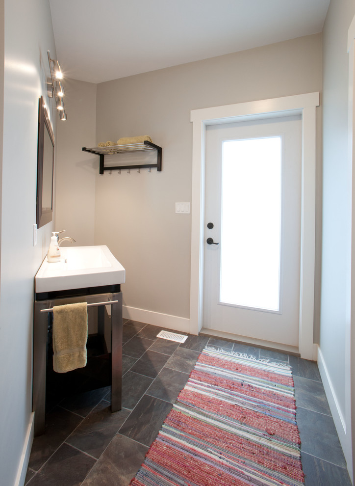 Foto de aseo clásico de tamaño medio con armarios abiertos, paredes grises, suelo de pizarra, lavabo integrado, puertas de armario grises y sanitario de una pieza