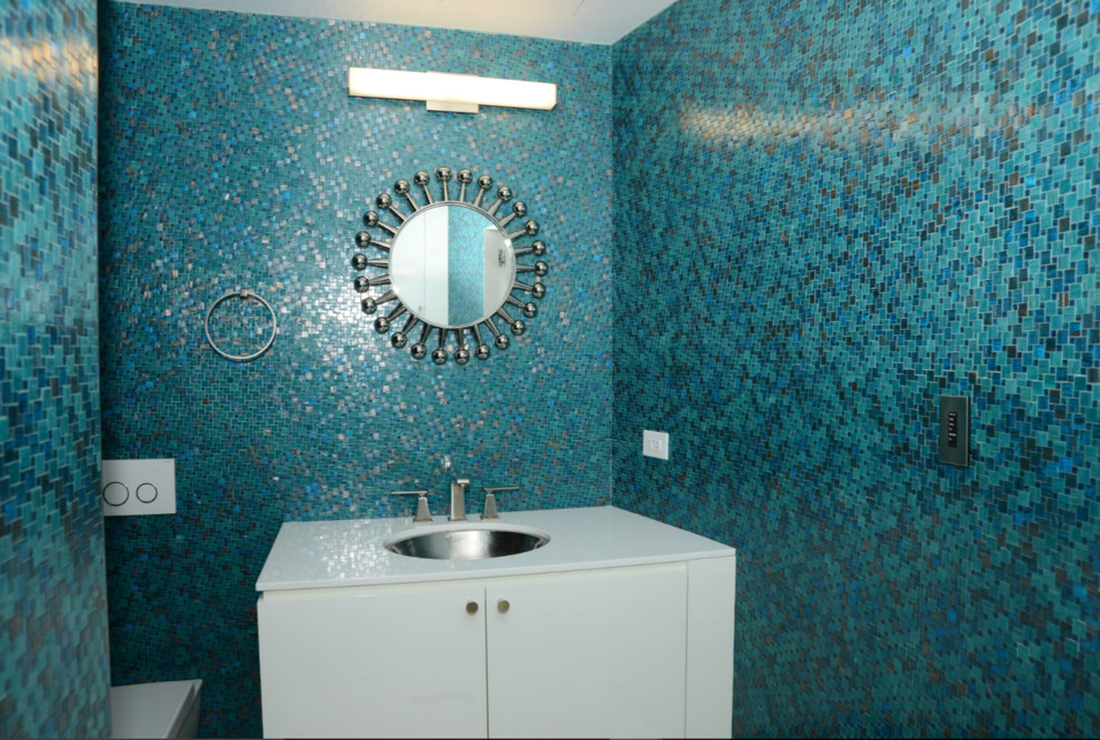 Kleine Moderne Gästetoilette mit flächenbündigen Schrankfronten, weißen Schränken, blauen Fliesen, Mosaikfliesen, bunten Wänden, Unterbauwaschbecken, Quarzwerkstein-Waschtisch und weißer Waschtischplatte in New York