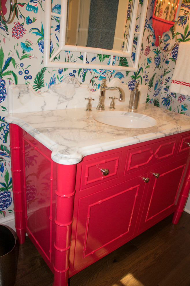 Eklektisk inredning av ett mellanstort toalett, med möbel-liknande, röda skåp, flerfärgade väggar, mörkt trägolv, ett undermonterad handfat, marmorbänkskiva och brunt golv