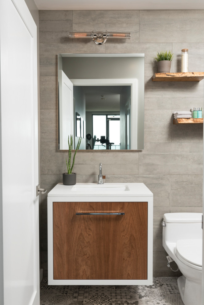 Small trendy gray tile mosaic tile floor and gray floor powder room photo in Toronto with flat-panel cabinets, medium tone wood cabinets, a one-piece toilet, gray walls, an undermount sink, white countertops and a floating vanity