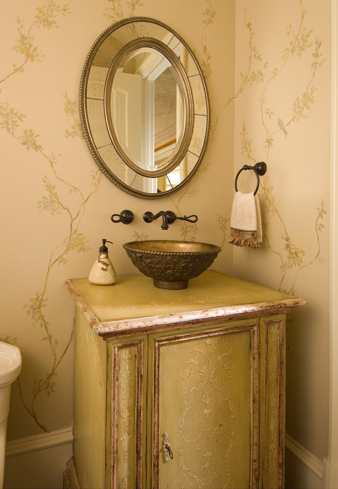 Inredning av ett medelhavsstil toalett, med ett fristående handfat, gröna skåp och beige väggar