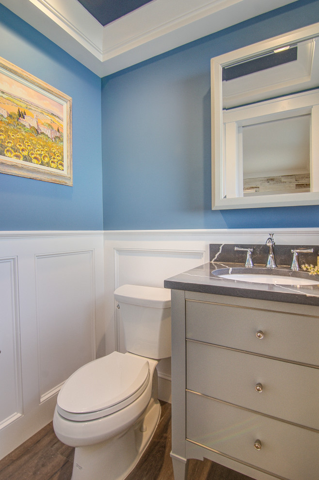 Photo of a small modern cloakroom in Other with flat-panel cabinets, grey cabinets, a two-piece toilet, blue walls, porcelain flooring, a submerged sink, engineered stone worktops, brown floors, black worktops, a freestanding vanity unit and wainscoting.