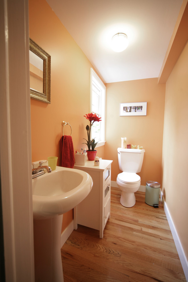 Ispirazione per un bagno di servizio tradizionale con ante bianche, WC a due pezzi, parquet chiaro, lavabo a colonna e pareti beige