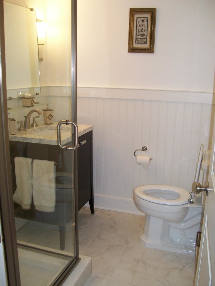 Ejemplo de aseo marinero con lavabo encastrado, encimera de mármol, sanitario de una pieza, baldosas y/o azulejos beige y paredes blancas