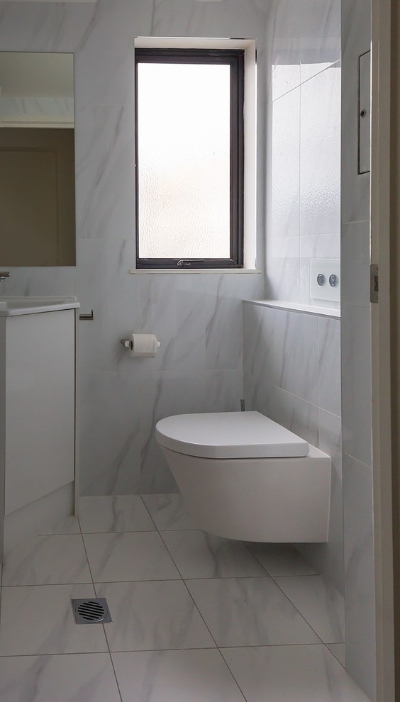 Inspiration for a small modern cloakroom in Sunshine Coast with a wall mounted toilet, white tiles, ceramic tiles, white walls, ceramic flooring, an integrated sink and white floors.