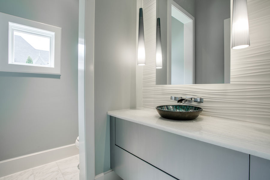 Aménagement d'un WC et toilettes contemporain de taille moyenne avec un carrelage blanc, un placard à porte plane, des portes de placard grises, un mur gris, un sol en marbre, une vasque et un plan de toilette blanc.
