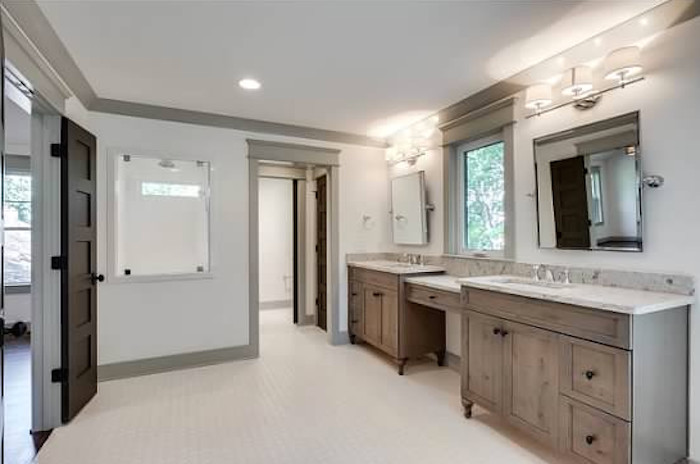 Réalisation d'un grand WC et toilettes minimaliste en bois clair avec un lavabo encastré, un placard avec porte à panneau encastré, un plan de toilette en marbre et un mur blanc.