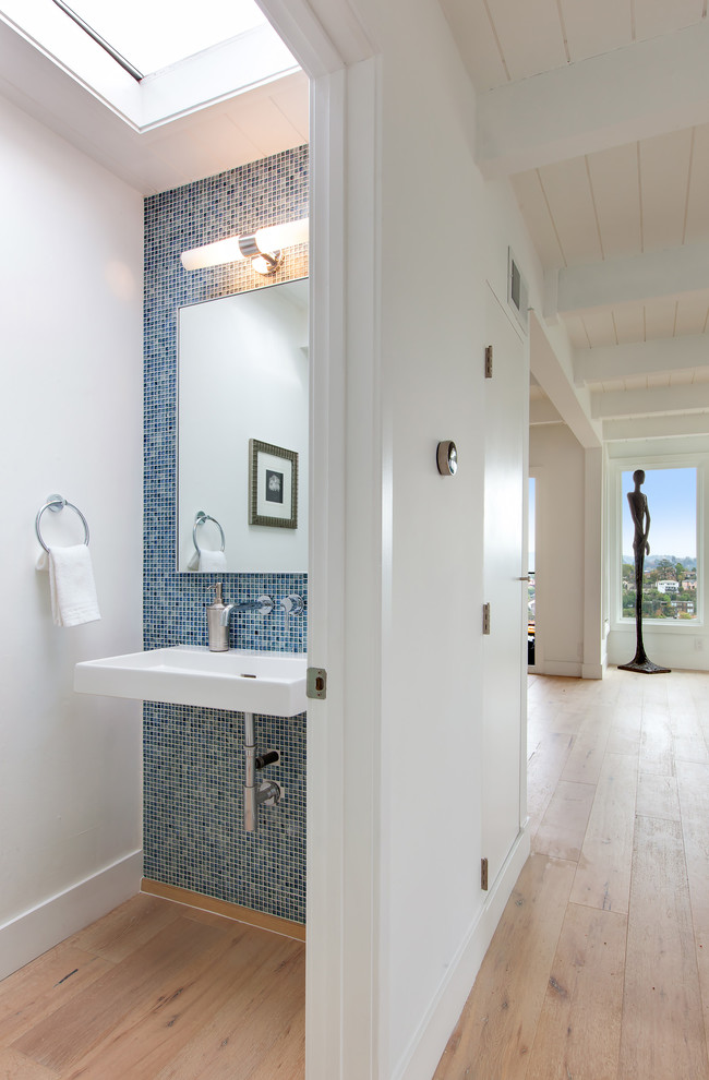 Свежая идея для дизайна: туалет в стиле неоклассика (современная классика) с синей плиткой, плиткой мозаикой, светлым паркетным полом, подвесной раковиной и белыми стенами - отличное фото интерьера