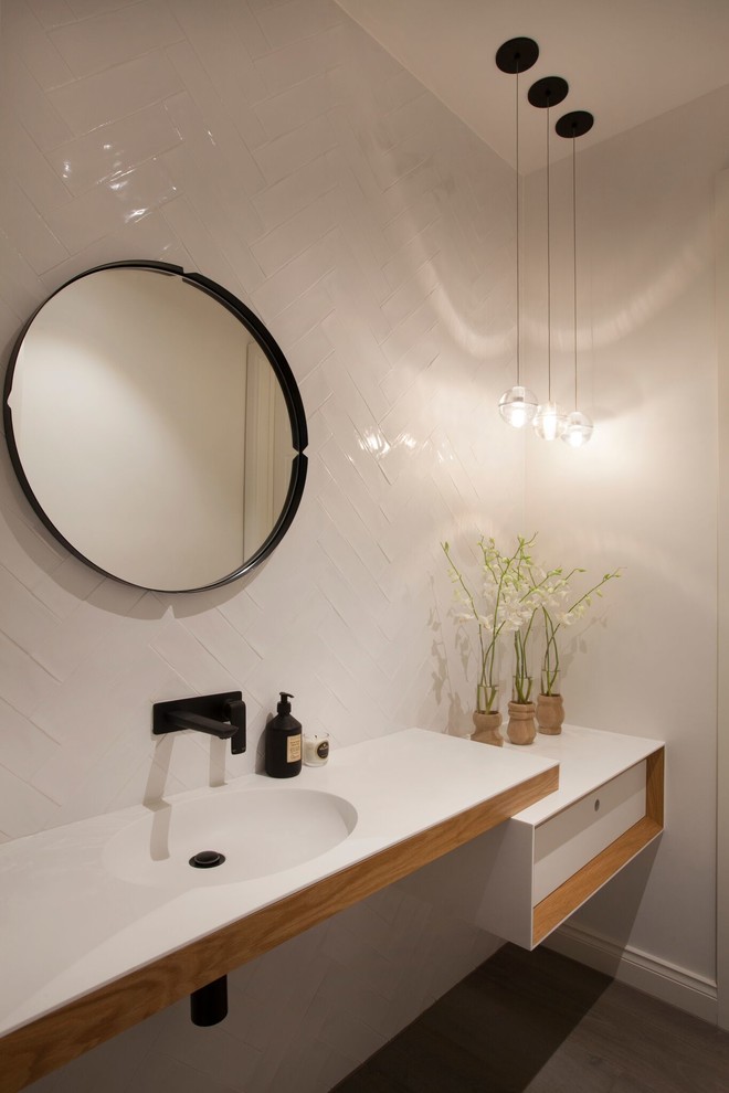 Пример оригинального дизайна: туалет в современном стиле с монолитной раковиной, белой плиткой и белой столешницей
