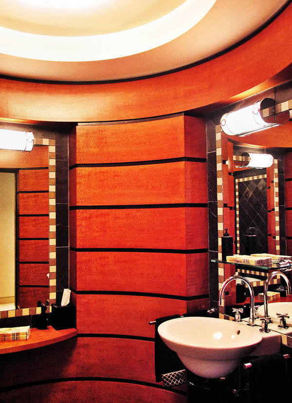 На фото: огромный туалет в стиле модернизм с фасадами островного типа, фасадами цвета дерева среднего тона, унитазом-моноблоком, разноцветной плиткой, каменной плиткой, раковиной с пьедесталом и столешницей из дерева