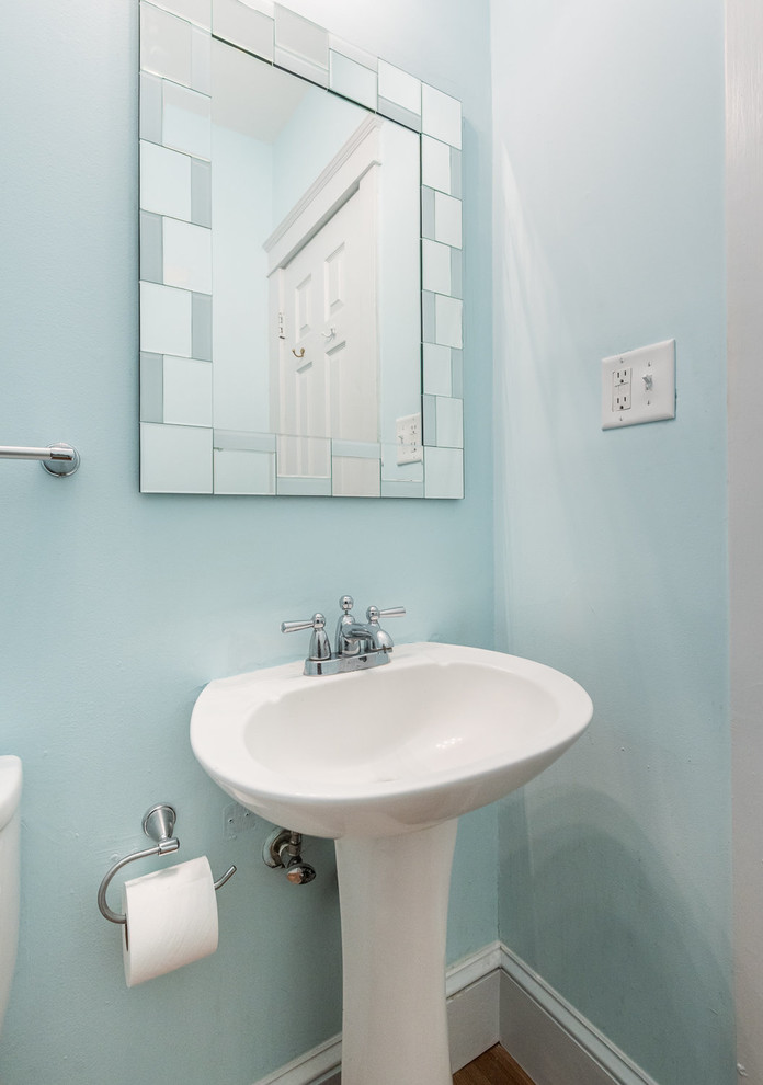 Immagine di un bagno di servizio tradizionale di medie dimensioni con pareti verdi, pavimento in legno massello medio, lavabo a colonna e pavimento marrone