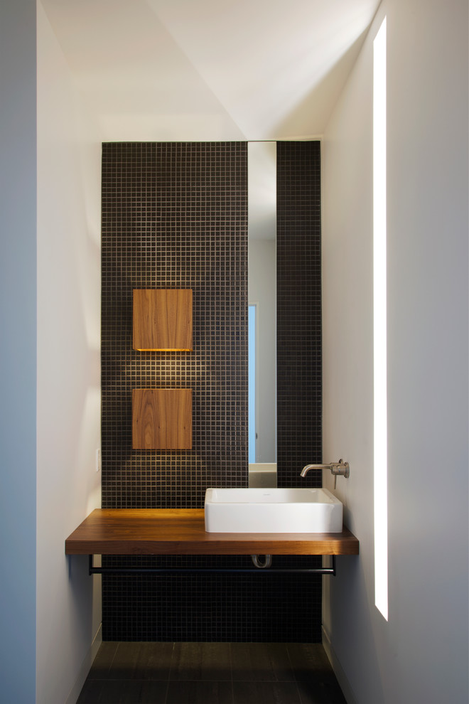 Foto de aseo moderno con lavabo sobreencimera, encimera de madera, baldosas y/o azulejos negros, baldosas y/o azulejos en mosaico, paredes blancas y encimeras marrones