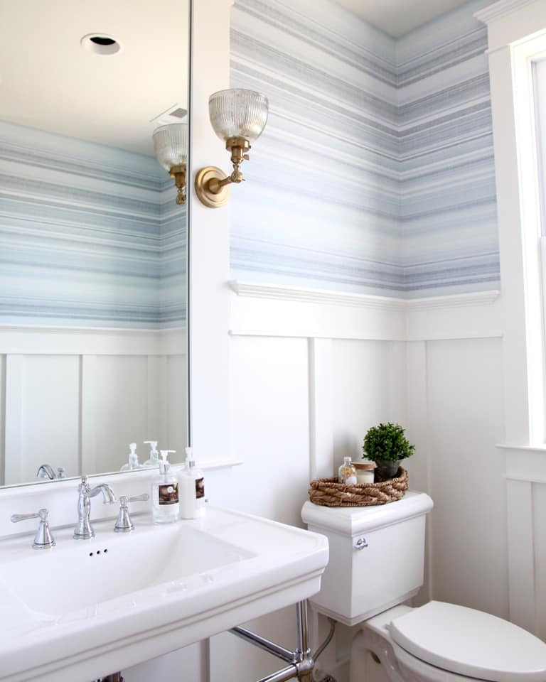 Powder room - coastal wallpaper powder room idea in DC Metro with blue walls, a pedestal sink, solid surface countertops and a freestanding vanity
