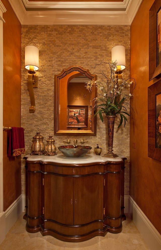 На фото: туалет в средиземноморском стиле с настольной раковиной, темными деревянными фасадами, бежевой плиткой, каменной плиткой и белой столешницей с