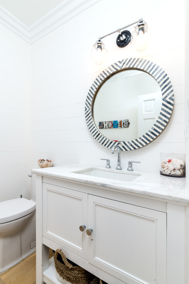 Immagine di un bagno di servizio chic di medie dimensioni con ante a filo, ante bianche, WC monopezzo, pareti bianche, parquet chiaro, lavabo sottopiano e top in marmo