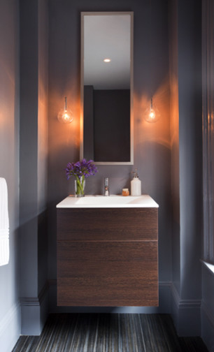 Modern inredning av ett vit vitt toalett, med släta luckor, skåp i mellenmörkt trä, grå väggar, ett integrerad handfat och bänkskiva i akrylsten