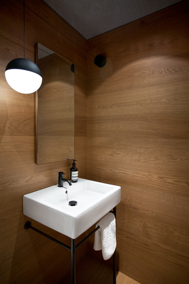 Inspiration för små minimalistiska toaletter, med ett piedestal handfat och mellanmörkt trägolv