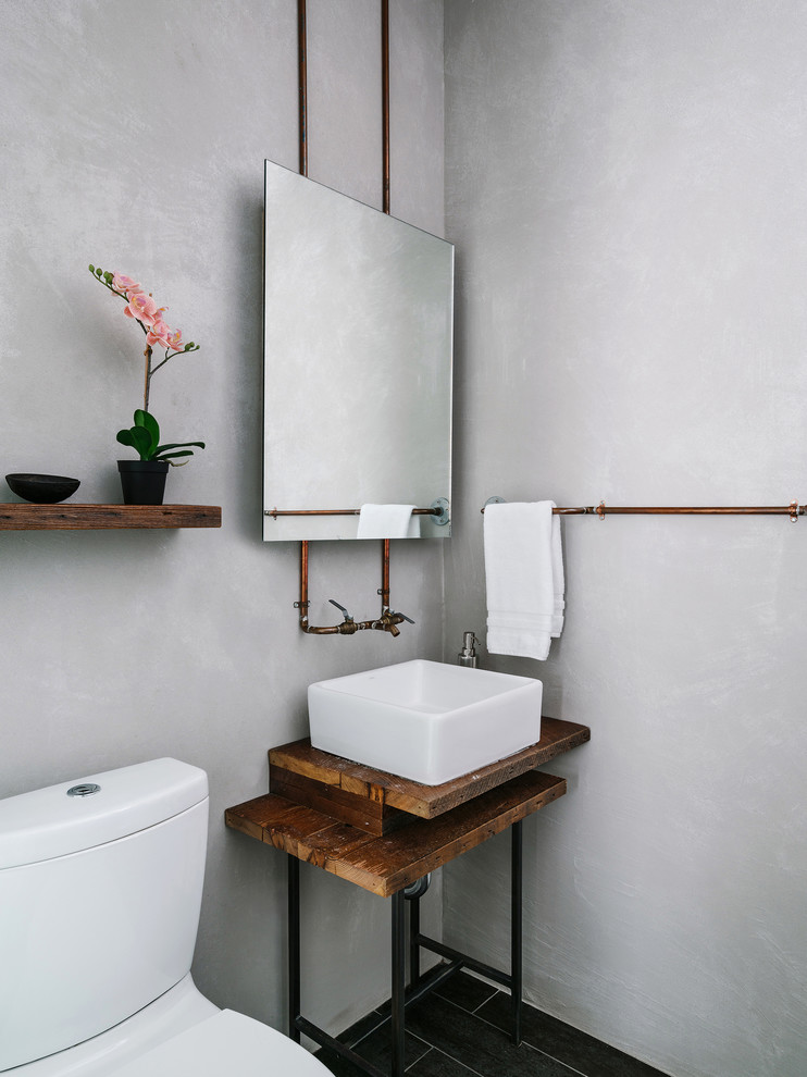 Urige Gästetoilette mit Wandtoilette mit Spülkasten, grauer Wandfarbe, Aufsatzwaschbecken, Waschtisch aus Holz und schwarzem Boden in Austin