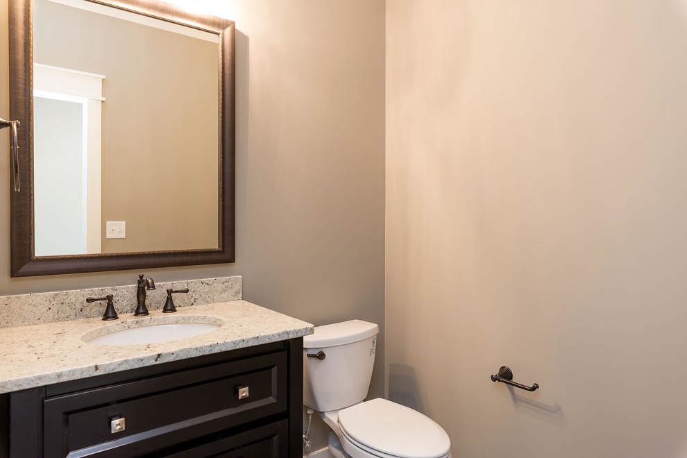Cette photo montre un WC et toilettes chic en bois foncé de taille moyenne avec un placard avec porte à panneau encastré, WC séparés, un mur beige, un lavabo encastré et un plan de toilette en granite.