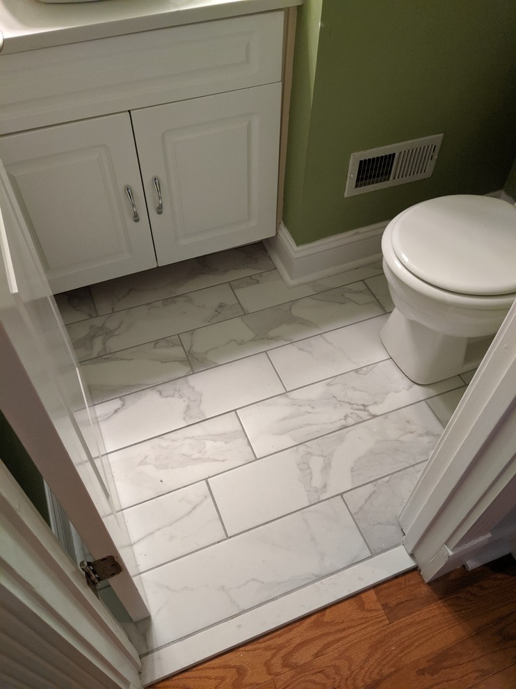 Cette image montre un petit WC et toilettes traditionnel avec un placard avec porte à panneau surélevé, des portes de placard blanches, un mur vert, un sol en marbre et un sol gris.