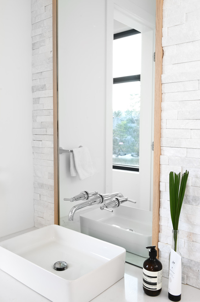 Moderne Gästetoilette mit flächenbündigen Schrankfronten, hellen Holzschränken, Toilette mit Aufsatzspülkasten, Steinfliesen, weißer Wandfarbe, braunem Holzboden, Aufsatzwaschbecken, Quarzit-Waschtisch und weißer Waschtischplatte in Vancouver