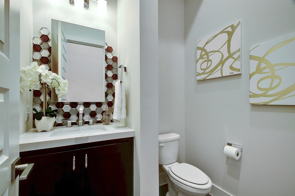 На фото: туалет в стиле неоклассика (современная классика) с фасадами в стиле шейкер, коричневыми фасадами, раздельным унитазом, разноцветной плиткой, плиткой мозаикой, белыми стенами, темным паркетным полом, врезной раковиной, мраморной столешницей, коричневым полом и белой столешницей