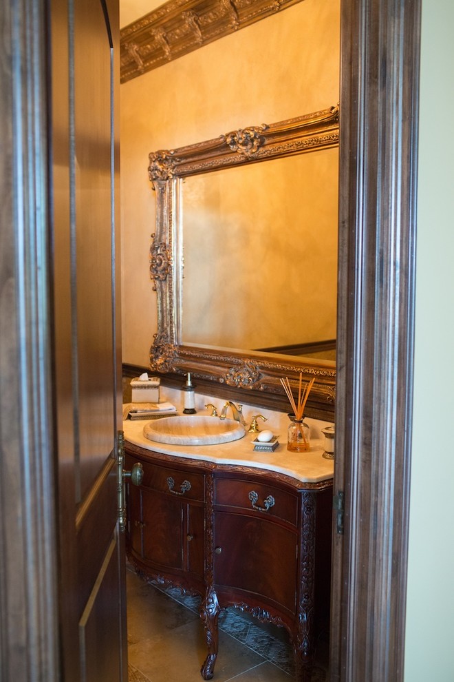 Exemple d'un grand WC et toilettes chic en bois foncé avec un lavabo posé, un placard en trompe-l'oeil, un plan de toilette en marbre, WC à poser, un carrelage beige, mosaïque, un mur beige et un sol en marbre.