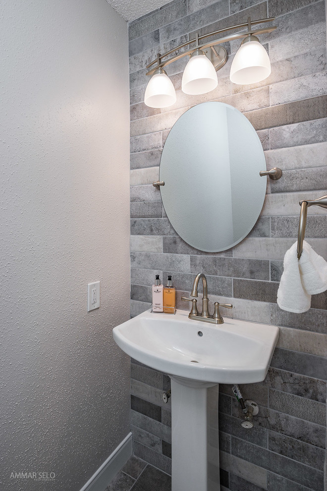 Photo of a small modern cloakroom in Houston with a two-piece toilet, grey tiles, porcelain tiles, grey walls, porcelain flooring, a pedestal sink and grey floors.