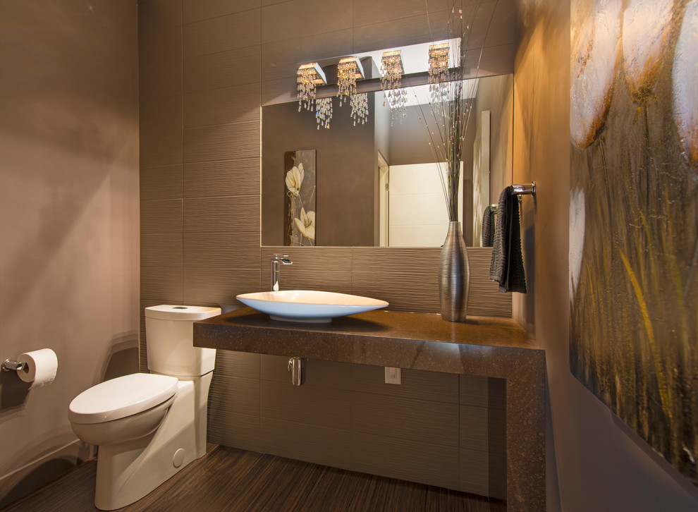 На фото: туалет среднего размера в современном стиле с раздельным унитазом, керамогранитной плиткой, настольной раковиной и столешницей из гранита с