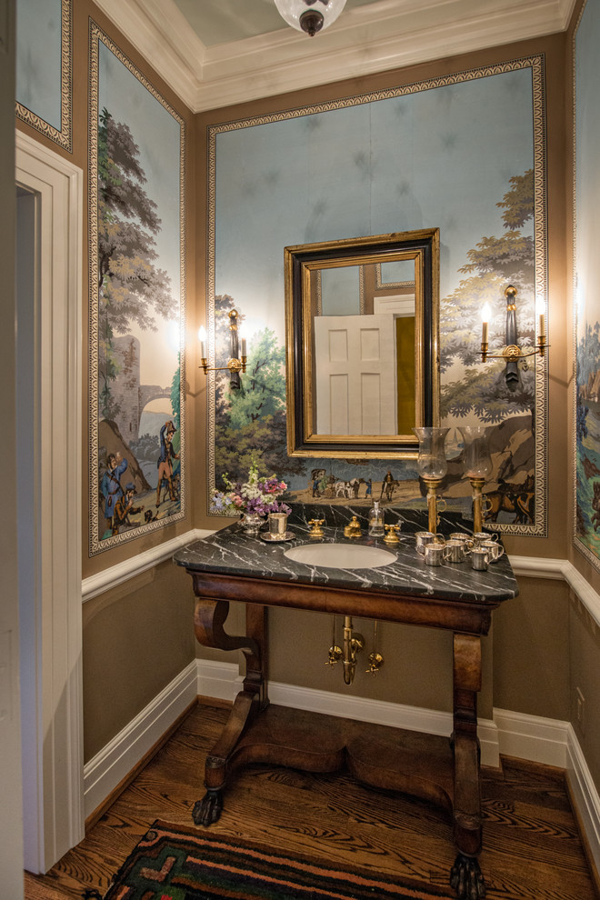 Cette photo montre un petit WC et toilettes chic en bois foncé avec un lavabo encastré, un placard en trompe-l'oeil, un plan de toilette en marbre, WC à poser, un mur multicolore et un sol en bois brun.