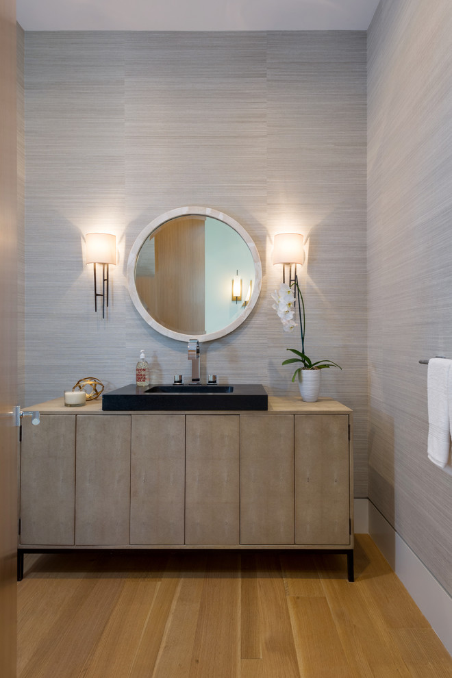 Foto på ett stort funkis toalett, med möbel-liknande, skåp i ljust trä, porslinskakel, grå väggar, ljust trägolv och ett fristående handfat
