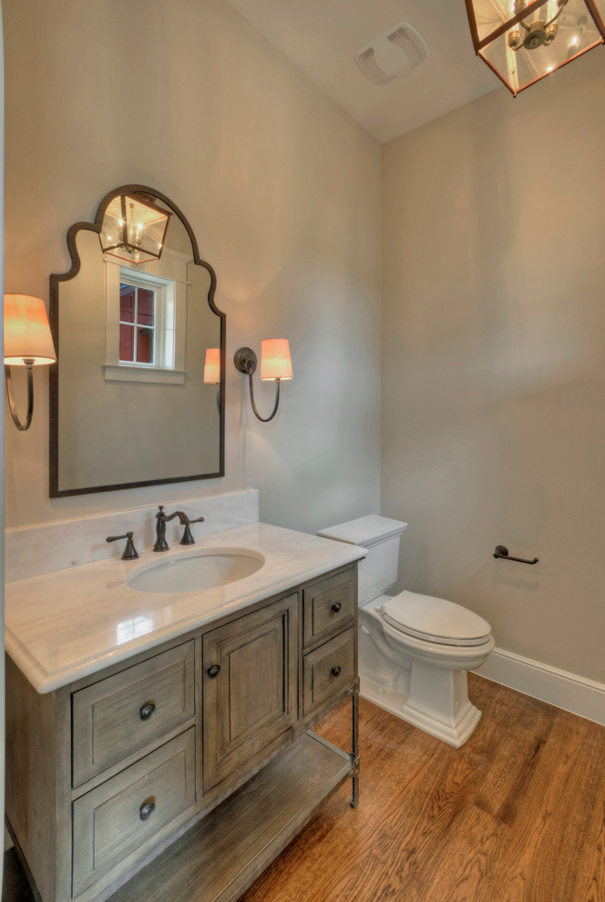 Immagine di un bagno di servizio country di medie dimensioni con lavabo sottopiano, consolle stile comò, ante beige, WC a due pezzi, pareti beige e pavimento in legno massello medio