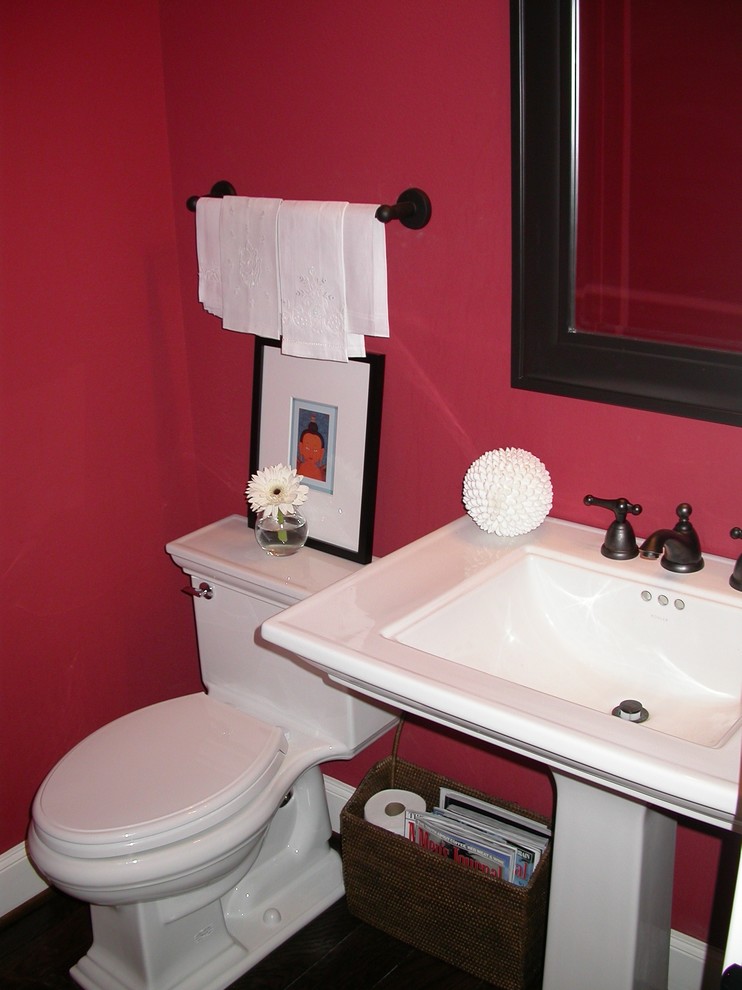 Kleine Klassische Gästetoilette mit rosa Wandfarbe, dunklem Holzboden, integriertem Waschbecken, Mineralwerkstoff-Waschtisch und braunem Boden in Sonstige