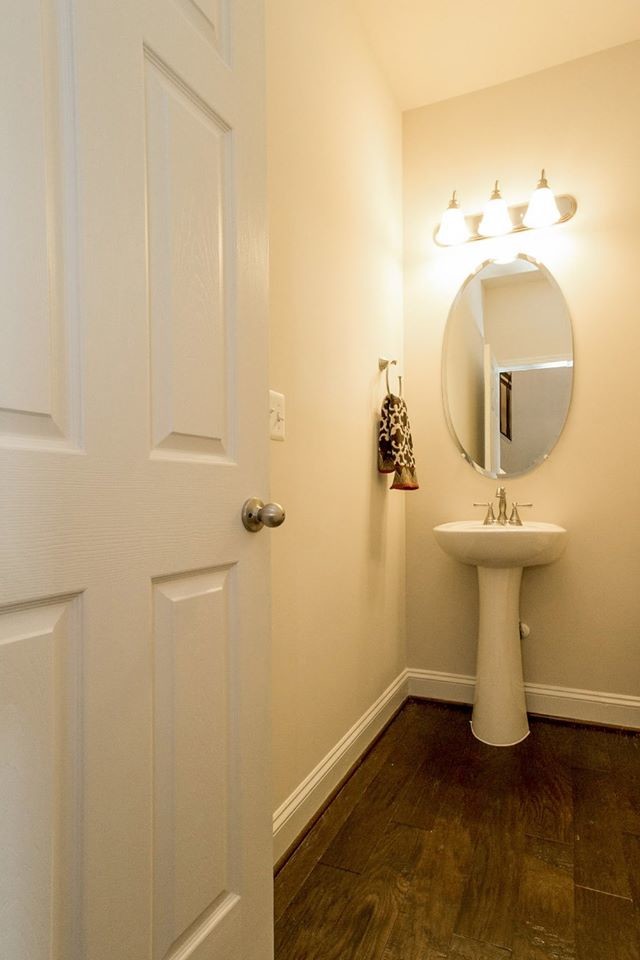 Klassisk inredning av ett litet toalett, med beige väggar, mörkt trägolv och ett piedestal handfat