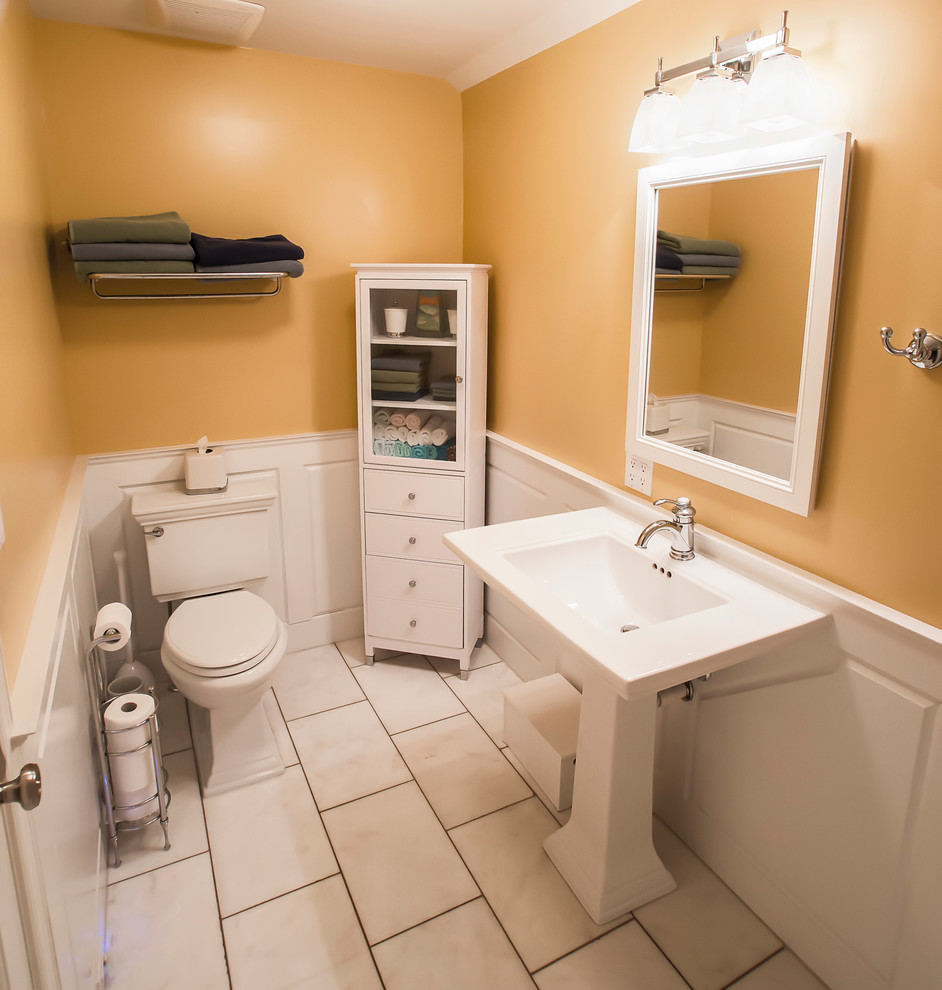 Design ideas for a classic cloakroom in DC Metro with a pedestal sink, flat-panel cabinets, white cabinets, a two-piece toilet, white tiles, yellow walls and marble flooring.