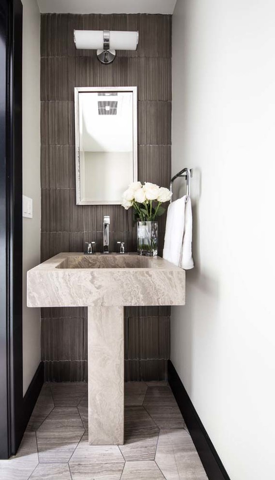 Modern inredning av ett litet toalett, med en toalettstol med hel cisternkåpa, grå kakel, cementkakel, vita väggar, travertin golv, ett piedestal handfat, marmorbänkskiva och grått golv