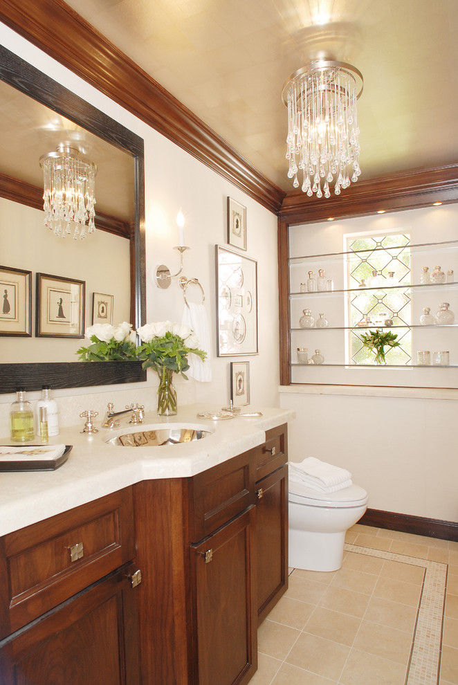 Esempio di un bagno di servizio classico con lavabo sottopiano, ante con riquadro incassato, ante in legno bruno e piastrelle beige