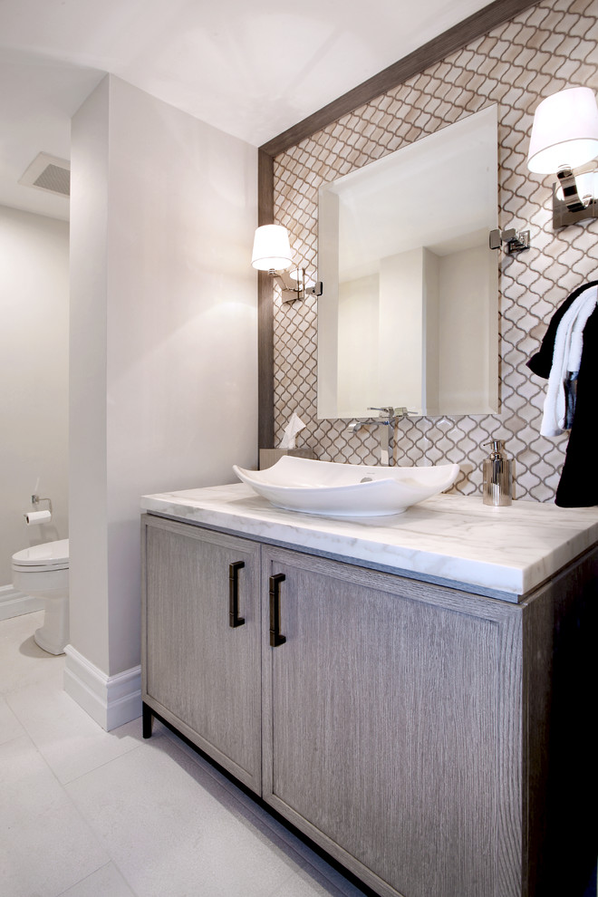 Example of a mid-sized transitional beige tile and mosaic tile powder room design in Los Angeles with a vessel sink, recessed-panel cabinets, light wood cabinets, marble countertops and beige walls