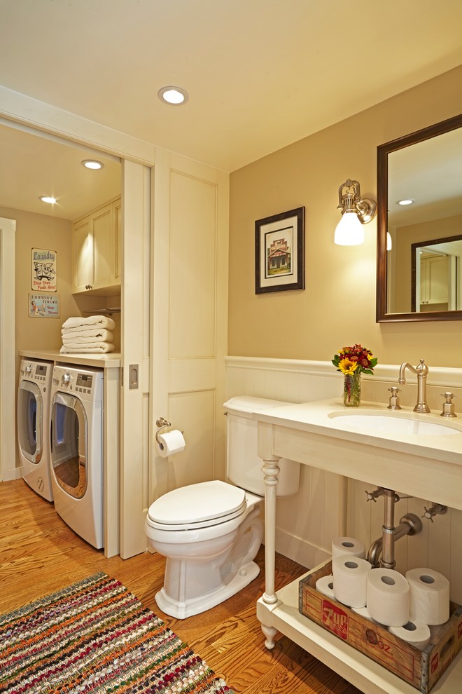 Klassisk inredning av ett litet toalett, med en toalettstol med separat cisternkåpa, beige väggar, mellanmörkt trägolv, ett undermonterad handfat, bänkskiva i kvarts, vita skåp och öppna hyllor