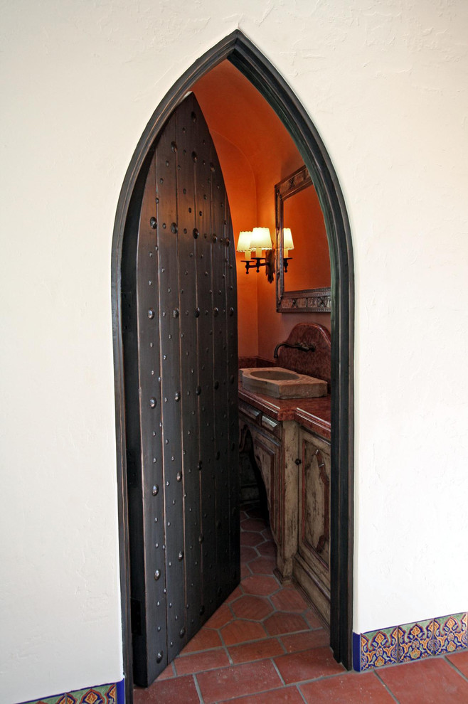 Mediterrane Gästetoilette mit verzierten Schränken, Schränken im Used-Look, Marmor-Waschbecken/Waschtisch und Terrakottaboden in San Diego