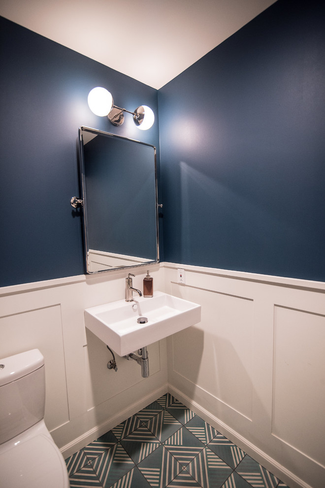 Bild på ett mellanstort vintage vit vitt toalett, med en toalettstol med hel cisternkåpa, blå väggar, cementgolv, ett väggmonterat handfat, bänkskiva i akrylsten och flerfärgat golv