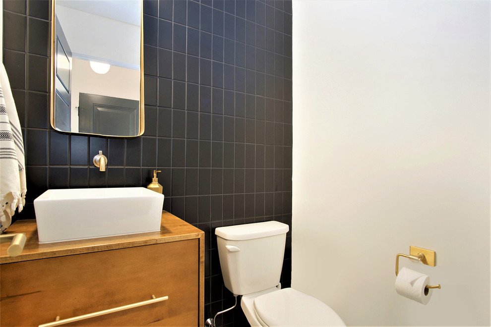 This is an example of a small scandinavian cloakroom in Grand Rapids with flat-panel cabinets, medium wood cabinets, a two-piece toilet, black tiles, ceramic tiles, red walls, a vessel sink, wooden worktops and brown worktops.