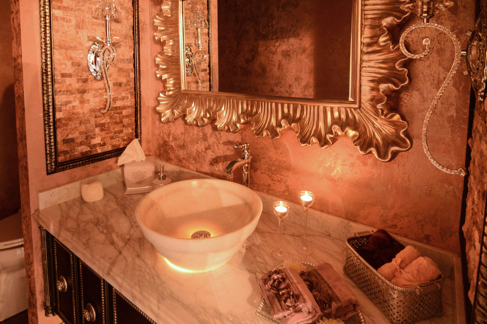 На фото: туалет в классическом стиле с настольной раковиной, темными деревянными фасадами, мраморной столешницей, унитазом-моноблоком, разноцветной плиткой, керамогранитной плиткой, розовыми стенами и полом из керамогранита с