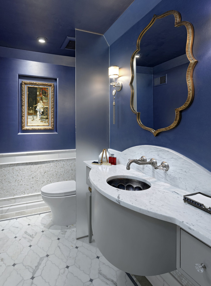 Aménagement d'un WC et toilettes méditerranéen avec un placard en trompe-l'oeil, des portes de placard grises, un carrelage blanc, du carrelage en marbre, un mur bleu, un sol en marbre, un lavabo encastré, un plan de toilette en marbre, un sol blanc et un plan de toilette blanc.