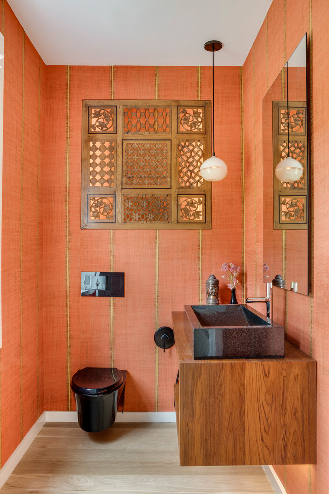 Mittelgroße Moderne Gästetoilette mit hellbraunen Holzschränken, hellem Holzboden, Waschtisch aus Holz, Wandtoilette, bunten Wänden, Aufsatzwaschbecken, beigem Boden und brauner Waschtischplatte in Boston