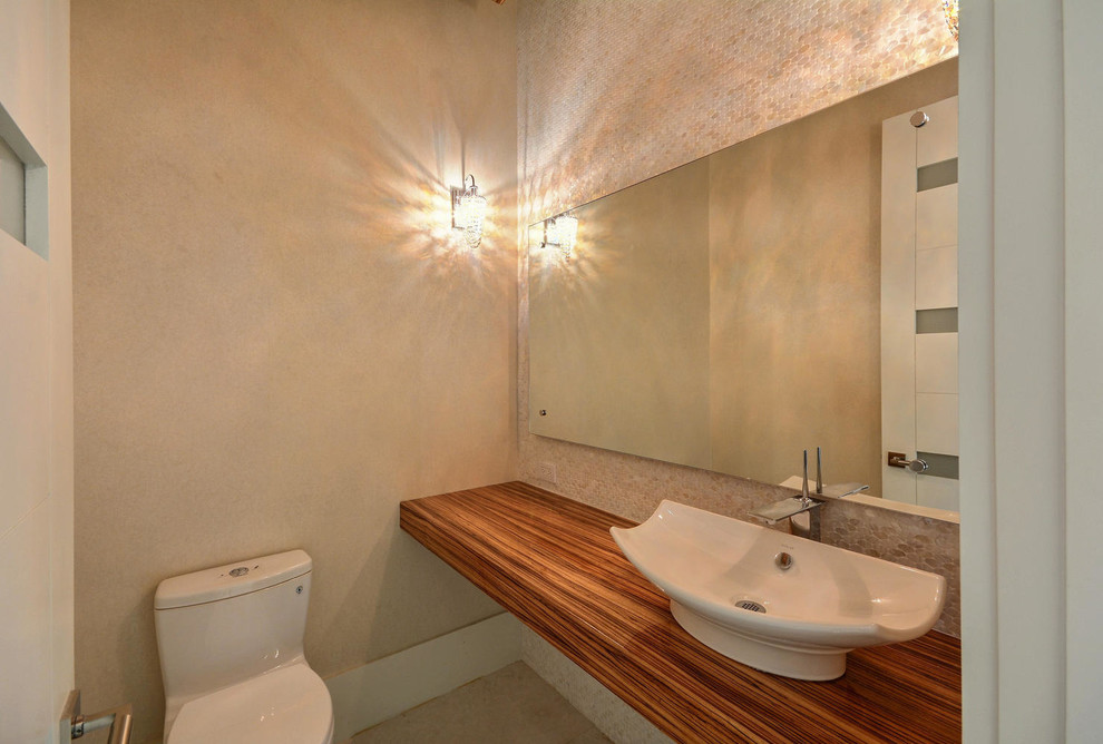 Immagine di un piccolo bagno di servizio contemporaneo con consolle stile comò, ante in legno chiaro, WC monopezzo, pareti beige, lavabo a bacinella e top in legno